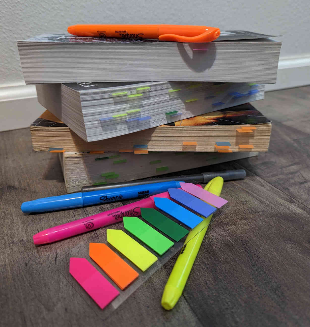 A stack of well-loved books with highlighters and sticky notes nearby.