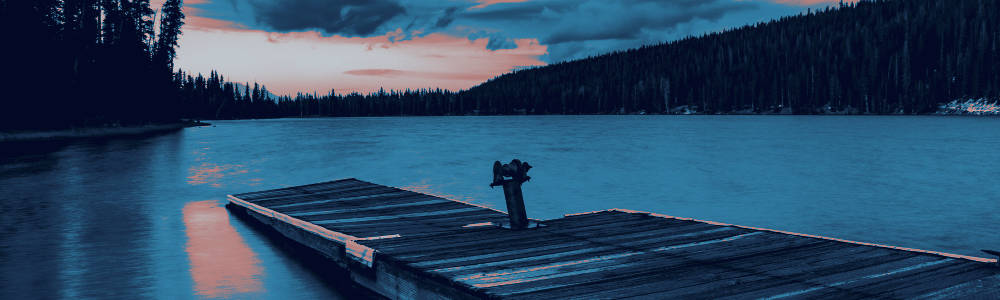 An old dock on a lake surrounded by evergreens.
