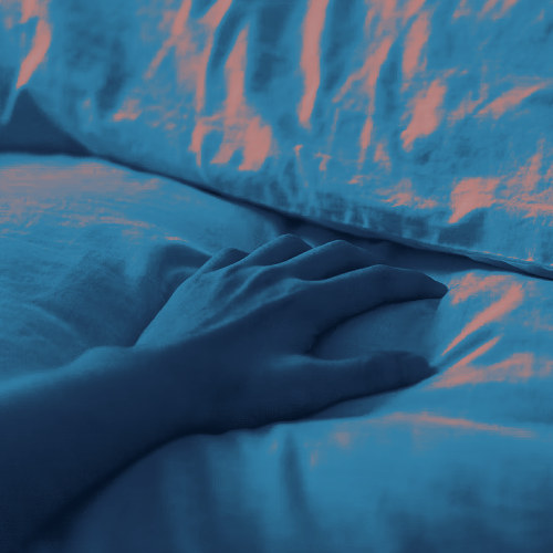 A hand reaches out toward a pillow.